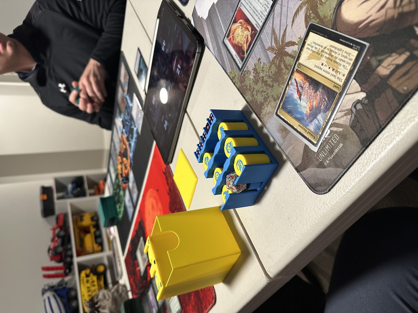 Players around a store table mid-Commander game, decks and counters spread out